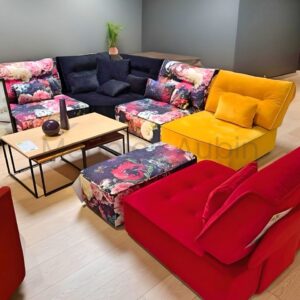 canape modulable multi chauffeuse rouge, jaune, tissu fleur, sur un parquet bois et mur noir