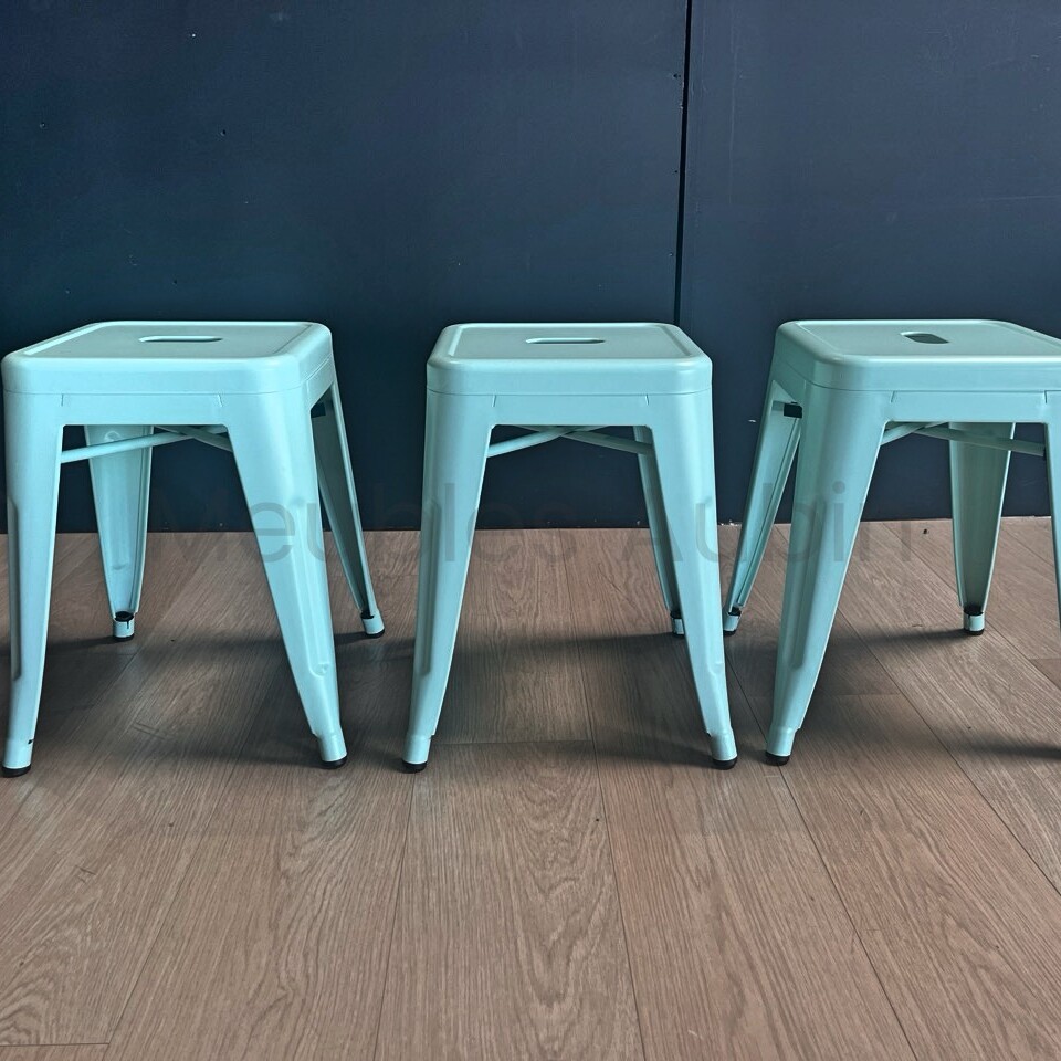 3 petits tabourets devant un mur noir sur un parquet bois clair